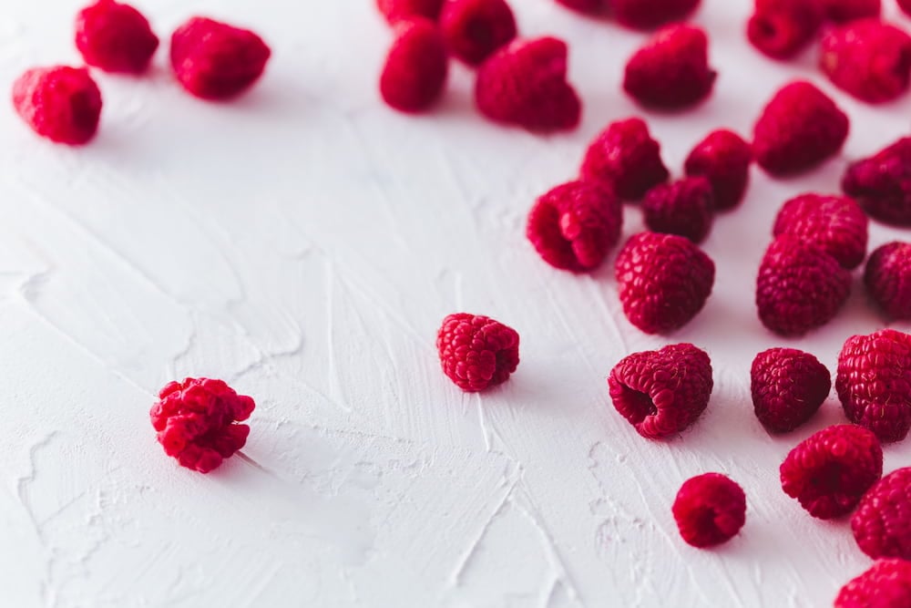 Close up shot of raspberries on white surface